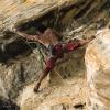 A climber reaches for a long clip on this rough 7a